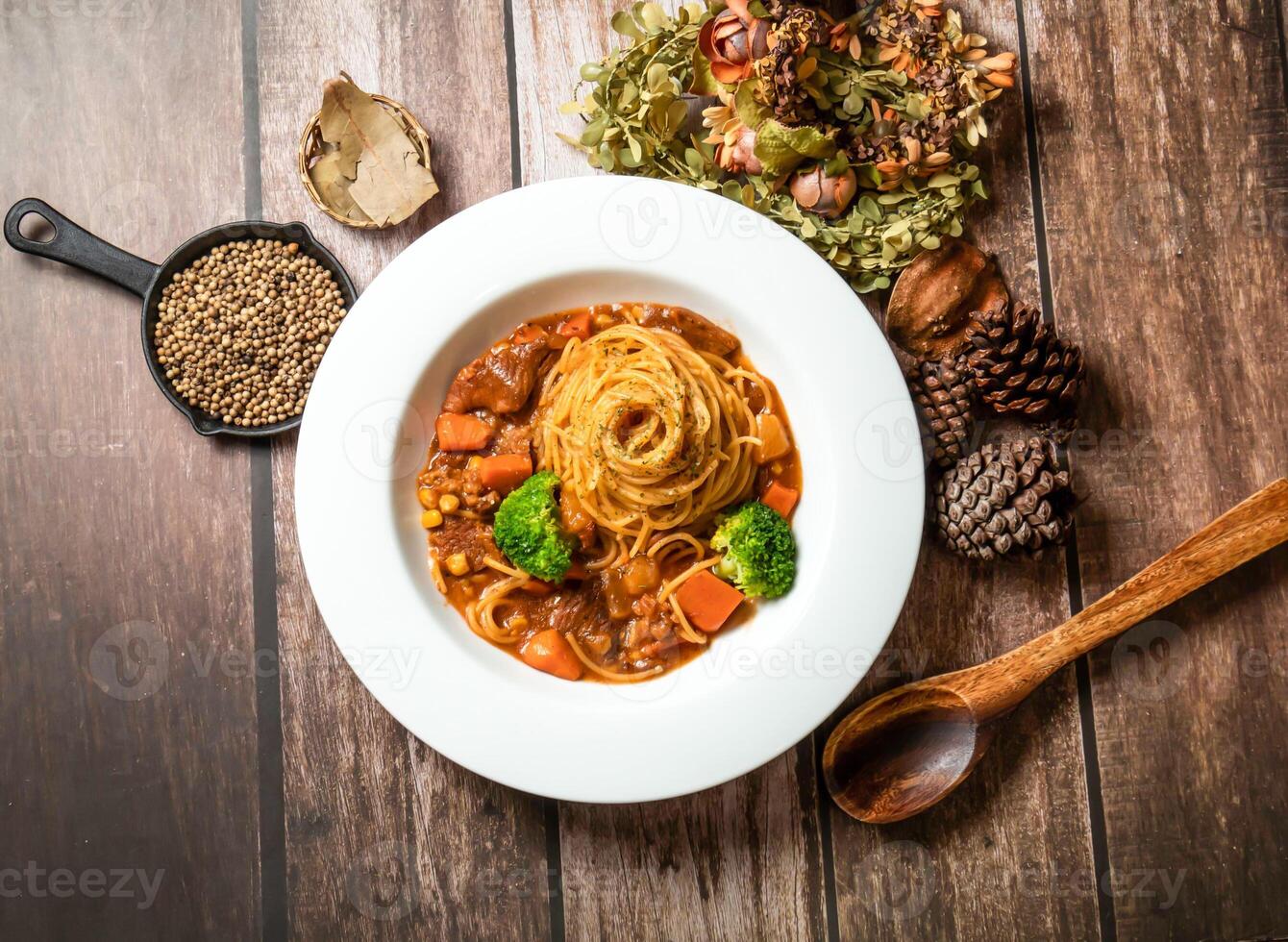 Red wine chicken noodles with carrot, broccoli, spoon and fork served in plate isolated on wooden table top view of taiwan fasfood photo