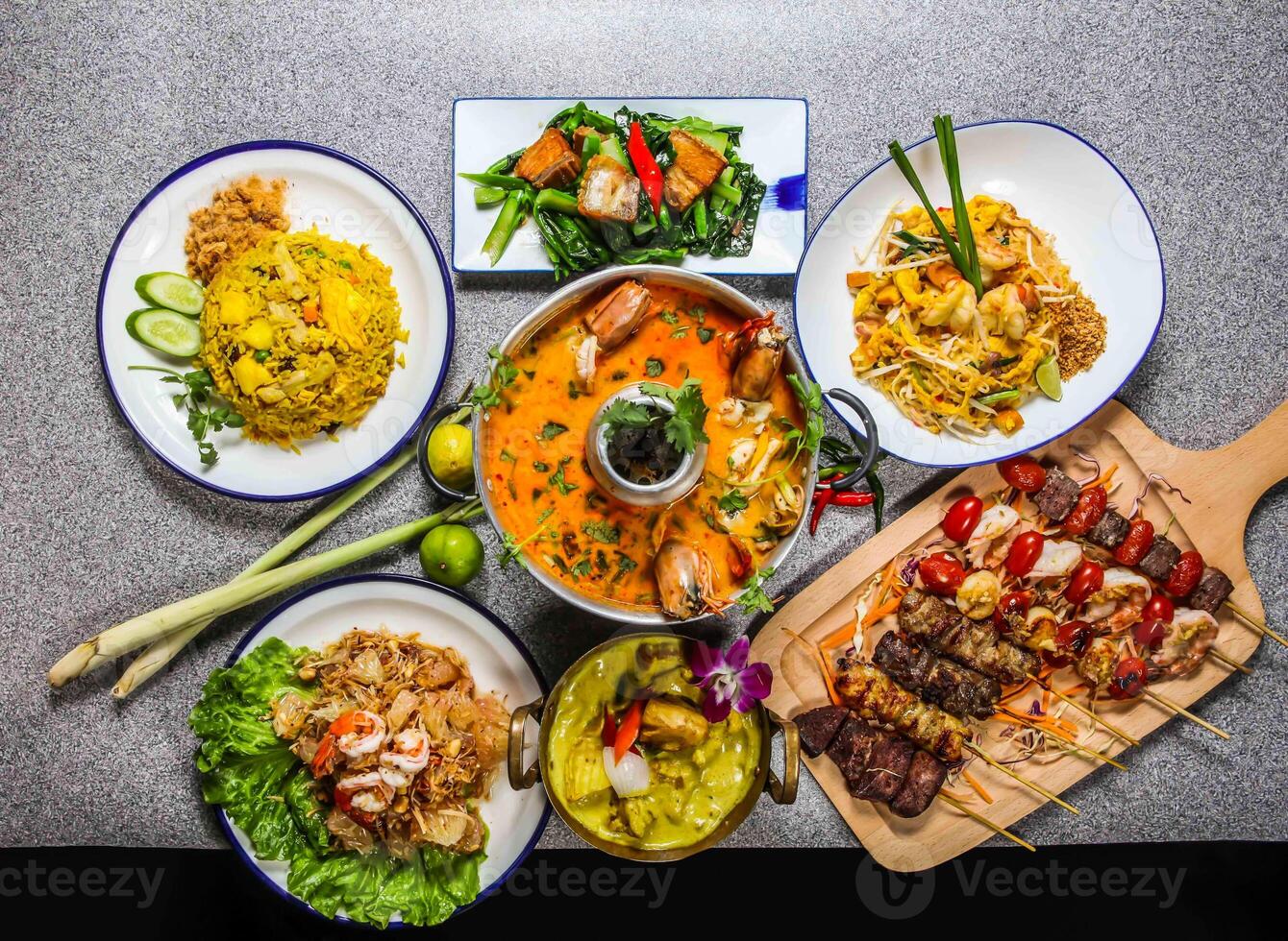 spicy tom yam soup king shrimps, yellow chicken curry, fried chinese kale with pork belly, thai fried noodles with shrimp, beef satay, skewer, pineapple rice, pomelo salad assorted food honk kong photo