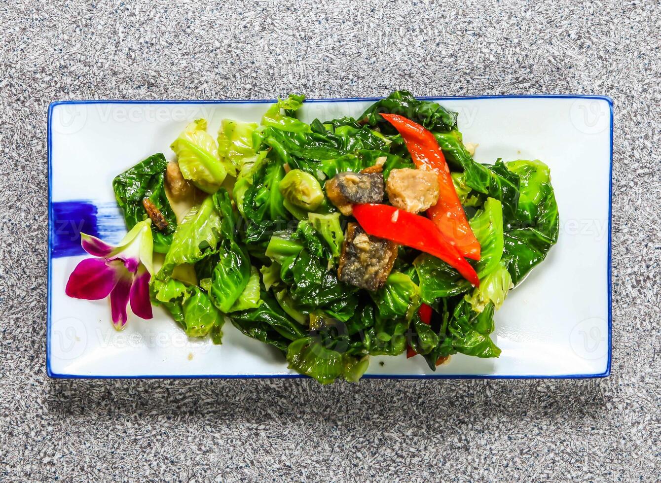 thai fried thai cabbage with salted fish, kale and red pepper served in tray dish isolated on grey background top view hong kong healthy green food photo