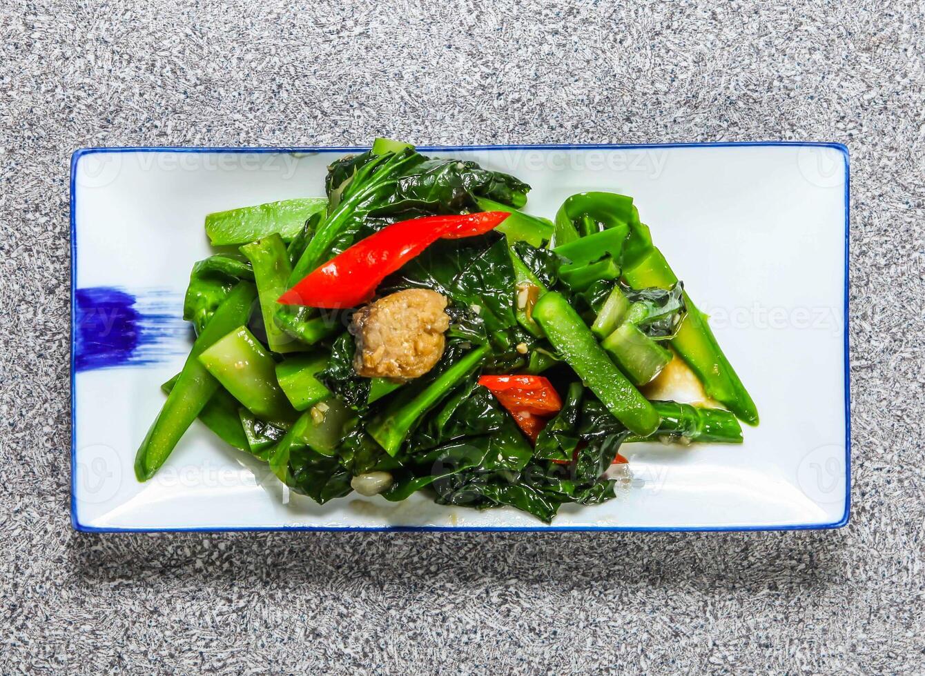 thai fried chinese kale with salted fish, kale and red pepper served in tray dish isolated on grey background top view hong kong healthy green food photo