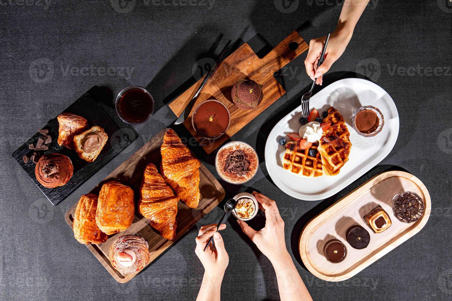 assorted cafe baked food variety Plain Croissant, chocolate pastry puff, CACAO Crispy Waffles, cacao tofu, Chocolate Puff, chocolate tart, with fork served isolated on dark background top view photo