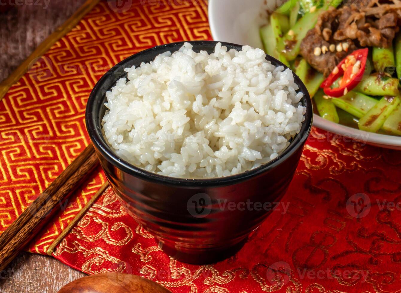 Boiled White Rice with chopsticks and spoon served in bowl isolated on napkin side view on wooden table of taiwanese food photo