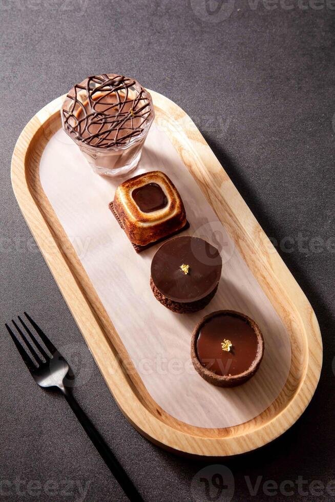 Single Origin Chocolate Flight Toasted Marshmallow Chocolate Tart, cacao Chocolate Puff balls, Chocolate Tart round, with fork served in dish isolated on dark background side view of baked cafe food photo