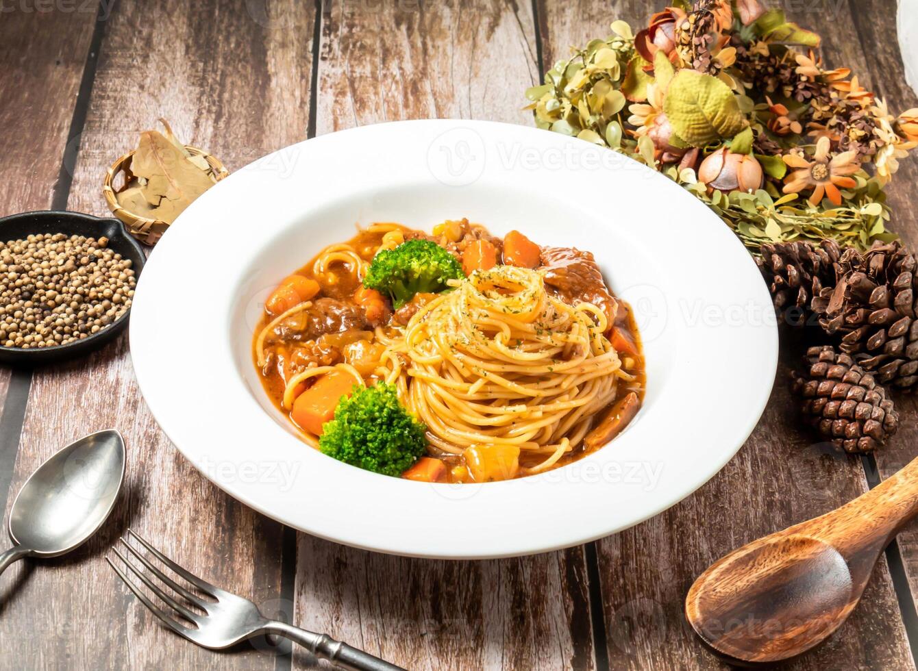 Beef Red Wine Noodles with carrot, broccoli, spoon and fork served in plate isolated on wooden table side view of taiwan fasfood photo