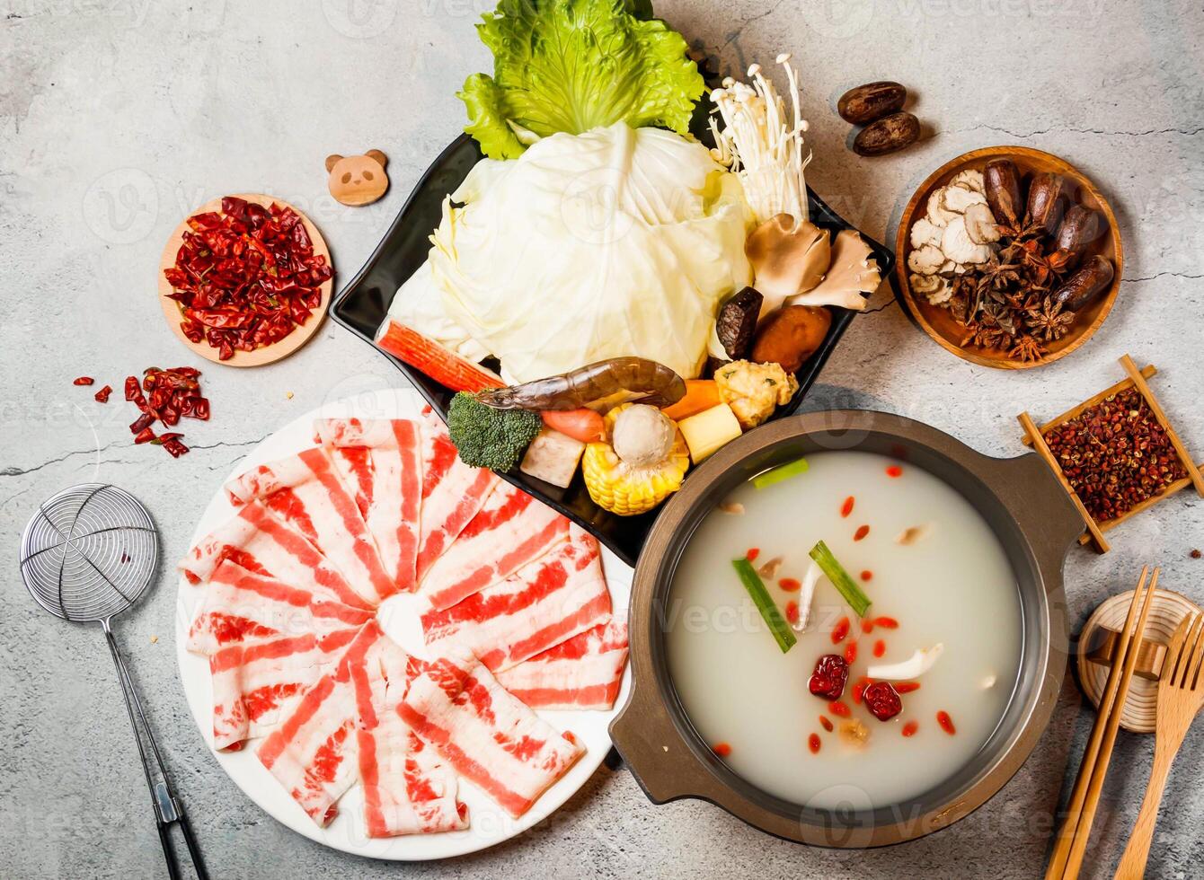 Clear soup pot set, cabbage, broccoli, mushroom, baby corn with red chilli, chopsticks and fork served in pot isolated on background side view of taiwanese food photo