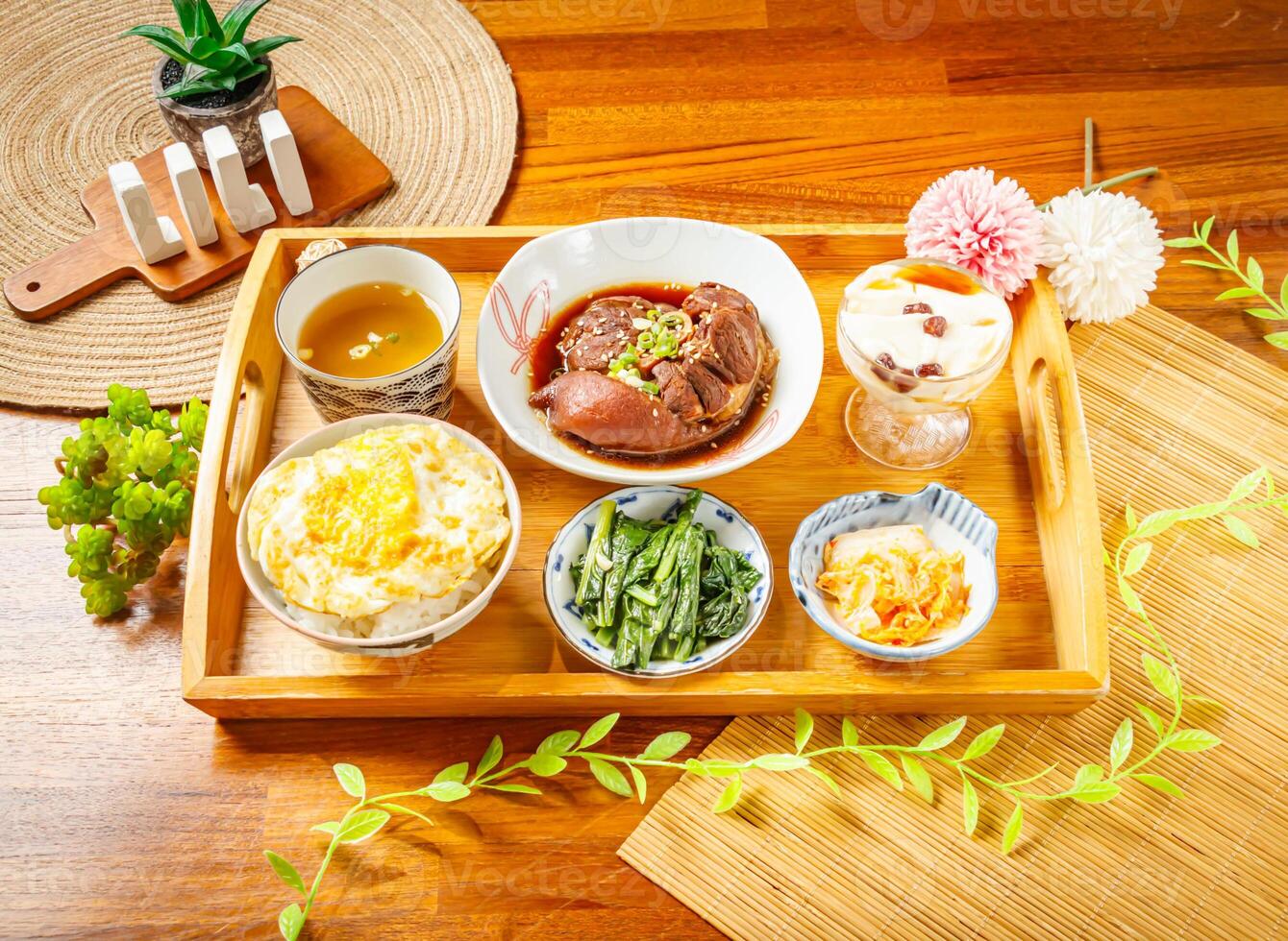 Braised pork knuckle rice, Miso soup, Braised pig feet, Tofu Pudding served in dish isolated on wooden table side view of taiwan food photo