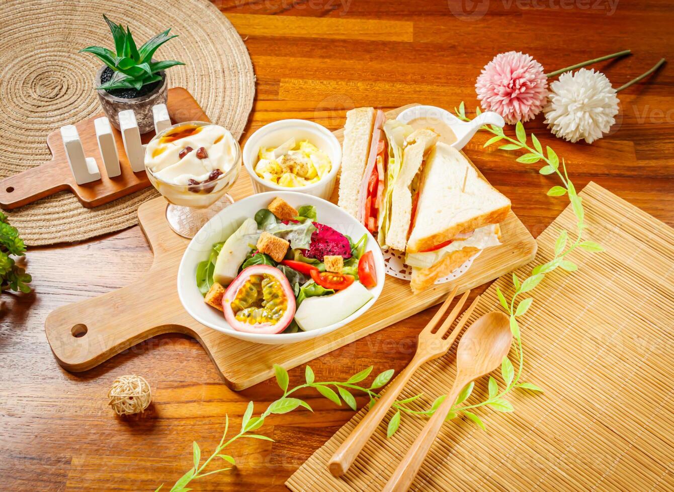 Vegetable and Fruit Salad with dragon fruit, passion fruit, cabbage, lettuce and tomato, club sandwich and Tofu Pudding served in dish isolated on wooden table side view of taiwan food photo