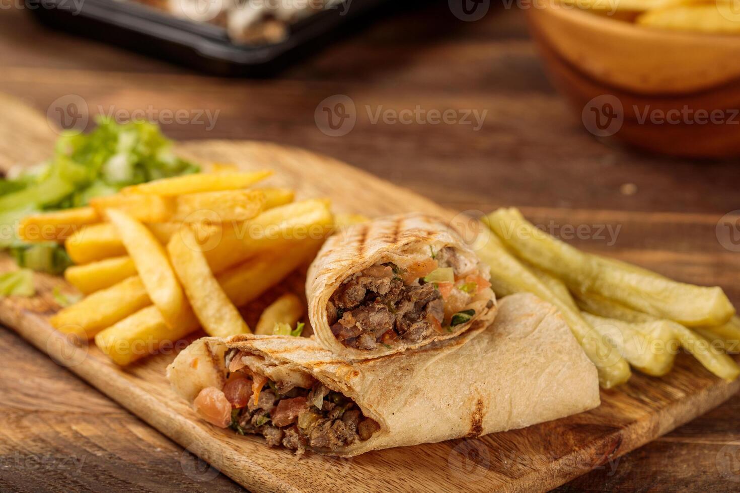 Beef Shawarma with french fries served in a cutting board isolated on wooden table background side view of fastfood photo