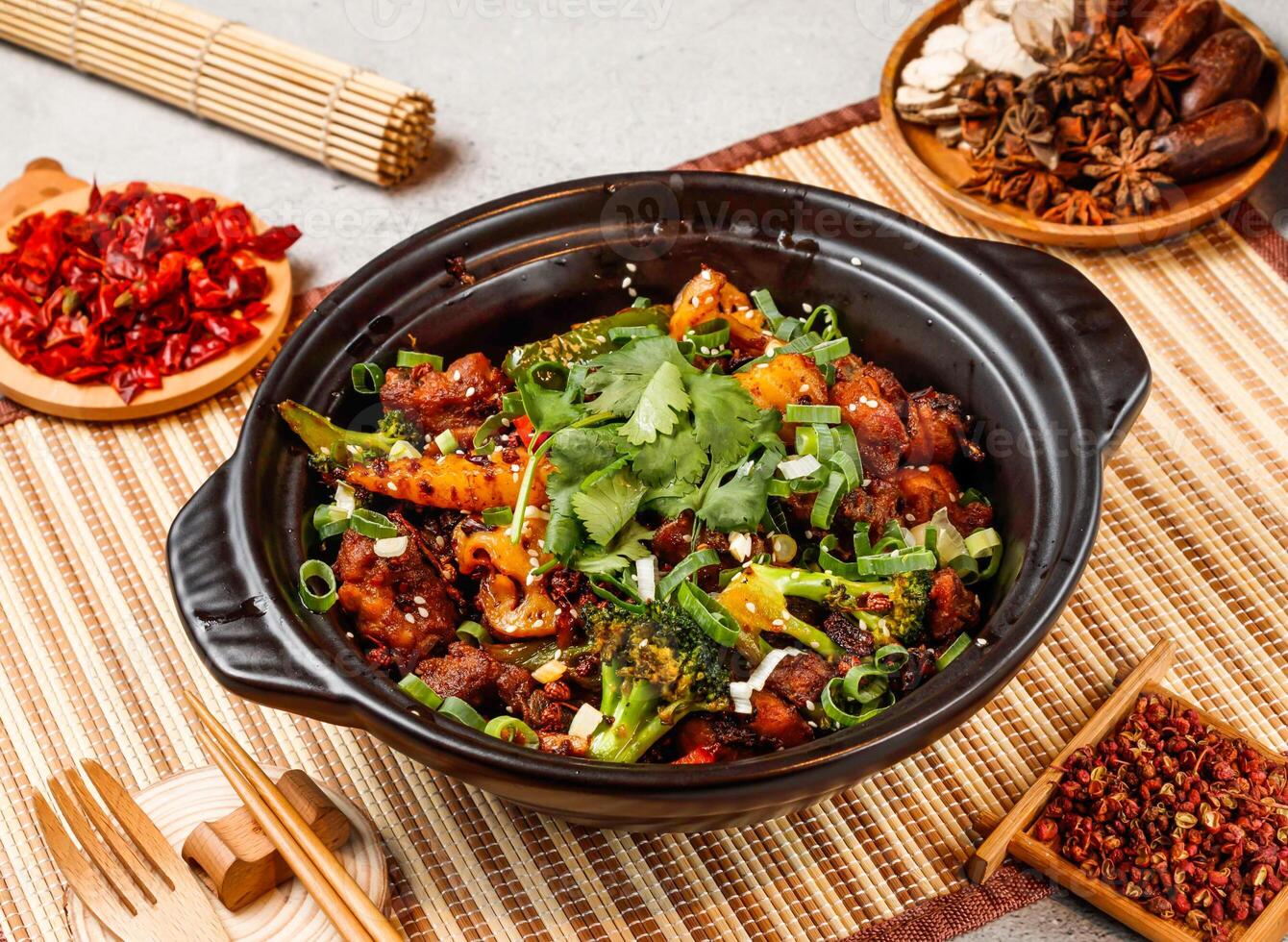Dry pot spare ribs with red chilli, chopsticks and fork served in pot isolated on background side view of taiwanese food photo