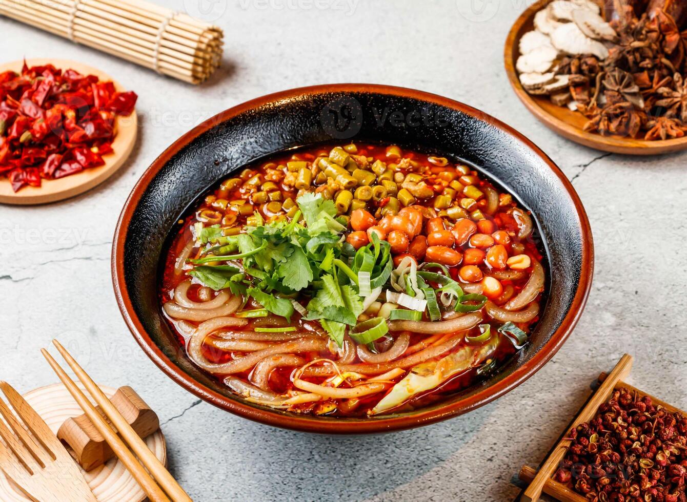 Hot and Sour Beans Noodles with coriander, red chilli, chopsticks and fork served in pot isolated on background side view of taiwanese food photo