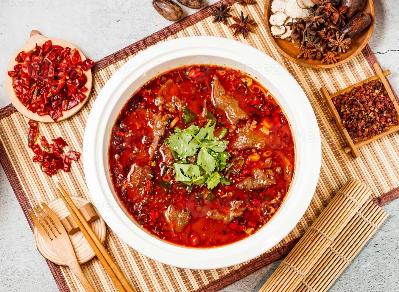 Spicy Boiled beef with coriander, red chilli, chopsticks and fork served in pot isolated on background side view of taiwanese food photo