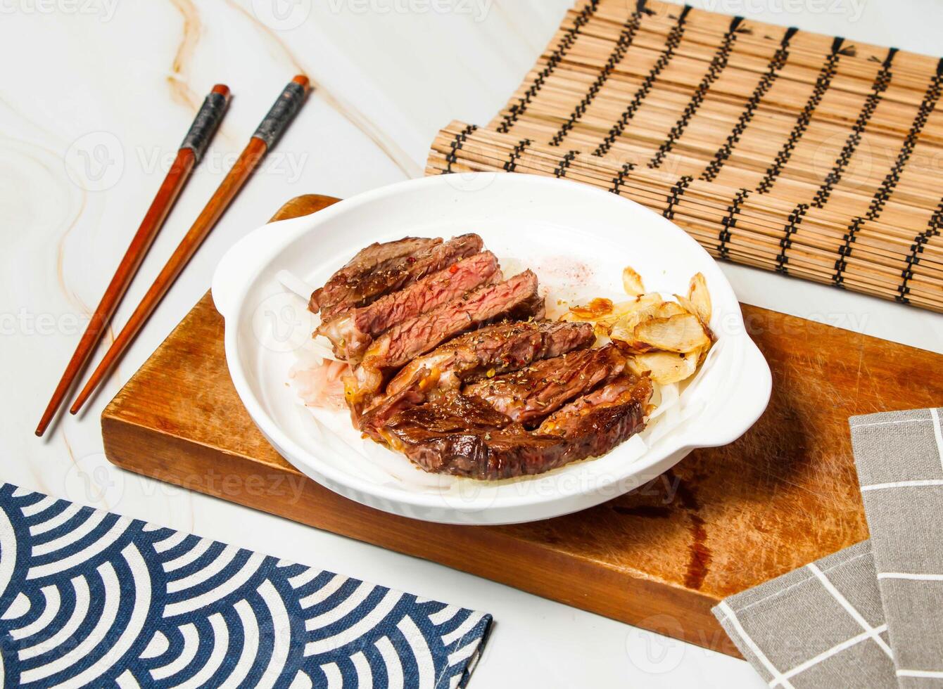 Grilled Sharon steak slice with chopsticks served in dish isolated on wooden board and napkin side view of taiwan food photo
