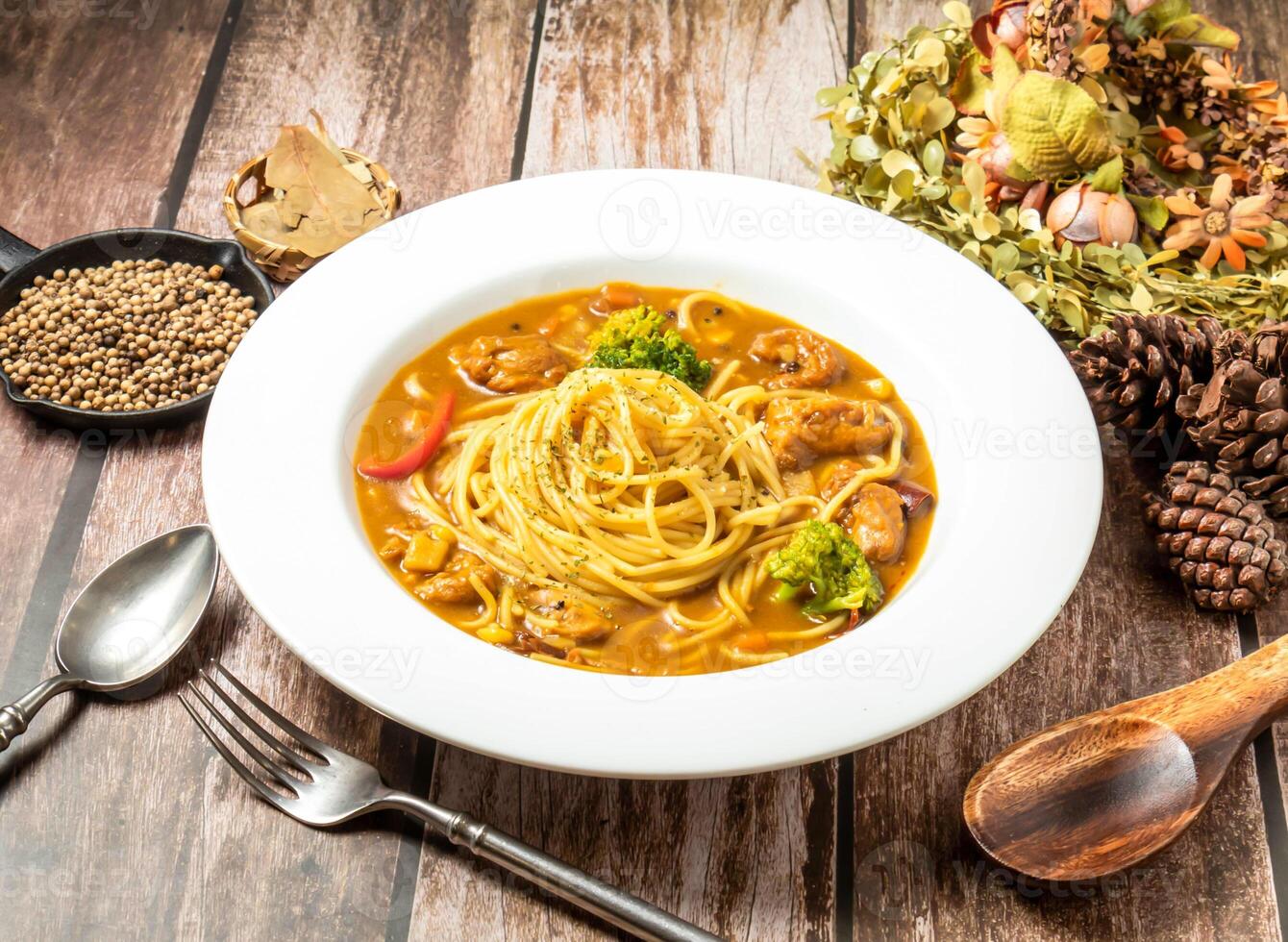 Japanese style curry chicken noodles with broccoli, spoon and fork served in plate isolated on wooden table top view of taiwan fasfood photo