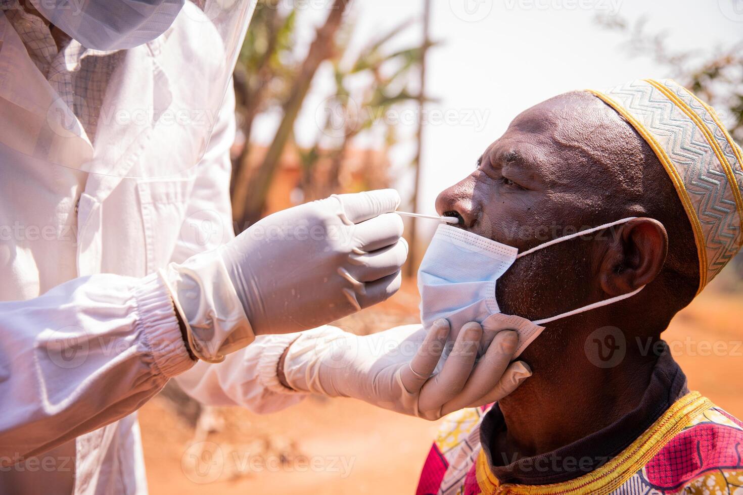 African senior man is tested for coronavirus with a swab inserted into his nose, healthcare and medicine in africa. photo