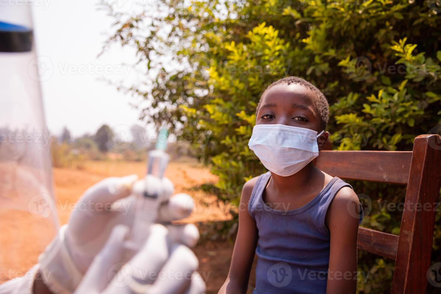 A doctor is about to vaccinate a child, close up on the child wearing a surgical mask photo