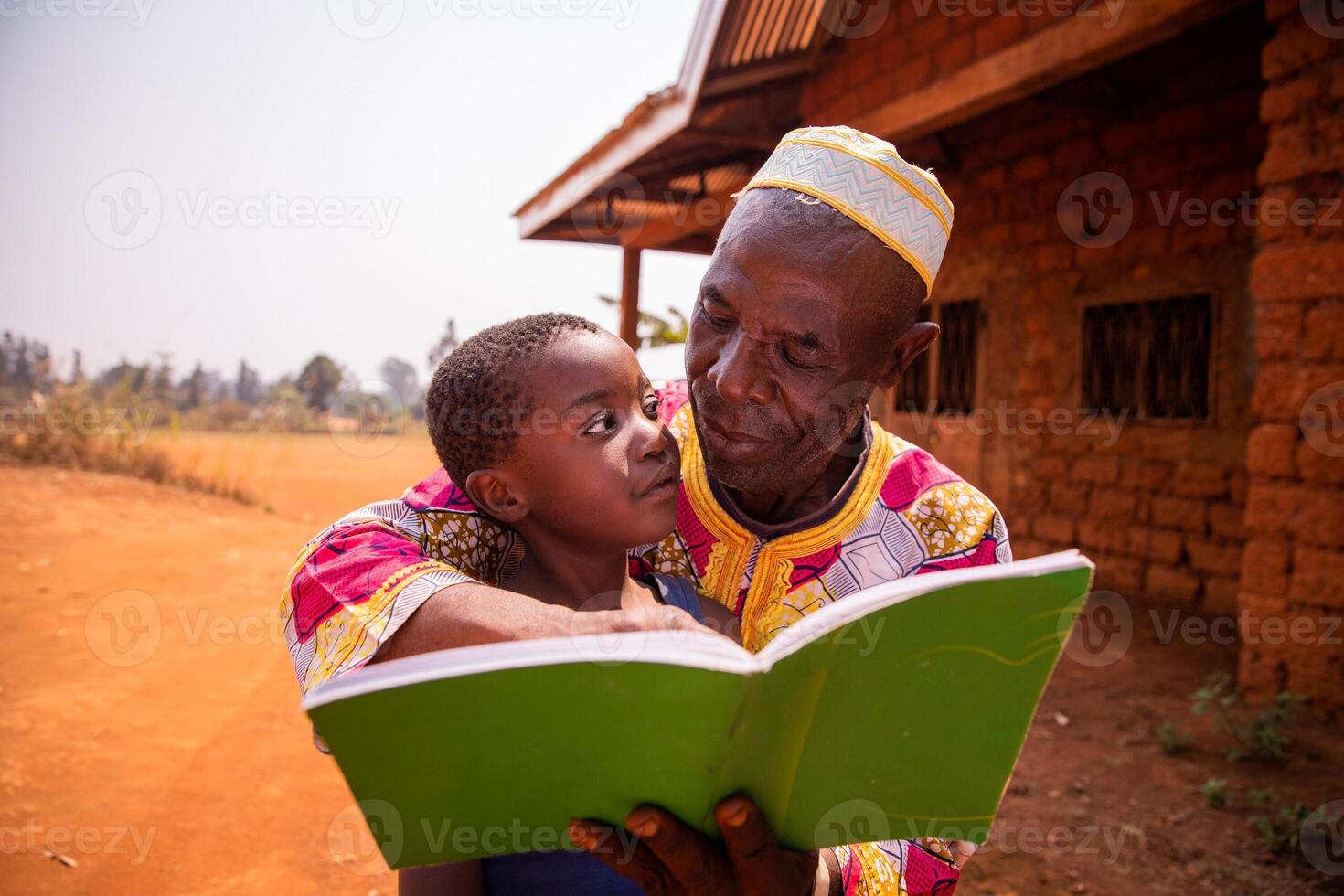 A grandfather reads fairy tales with his grandson in Africa, a moment of affection between grandfather and grandson photo