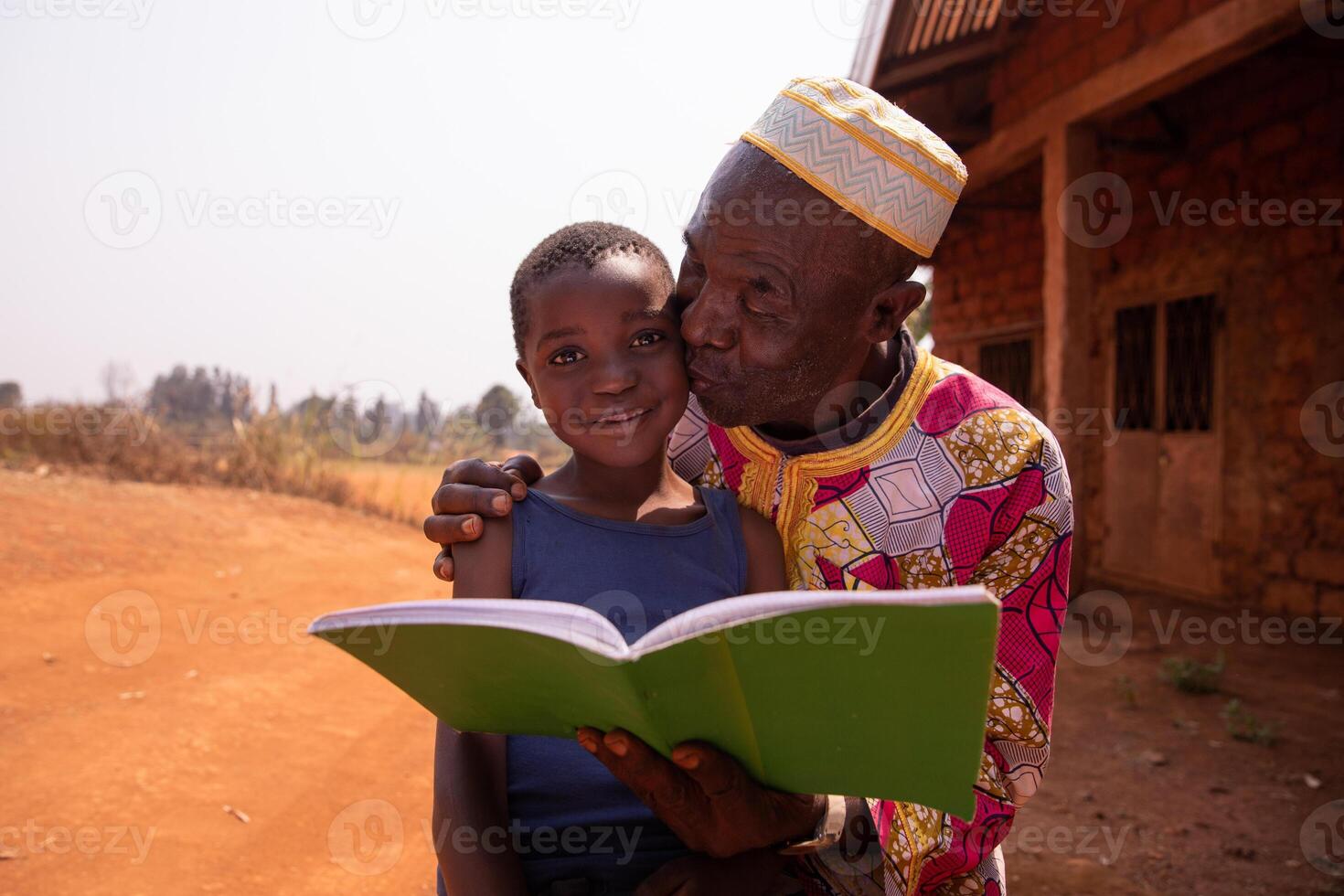African grandfather kisses his grandson as they read a book together. Love between grandfather and grandson photo