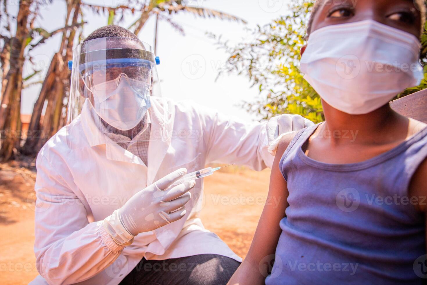 African child taking vaccine against coronavirus in an outdoor hub in the village photo