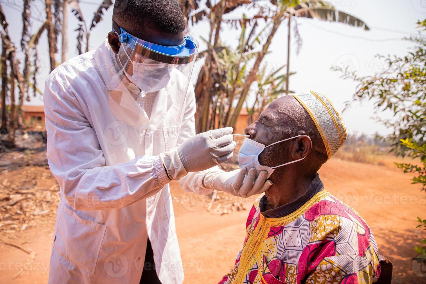 An African doctor performs a nasal swab test on an elderly patient photo