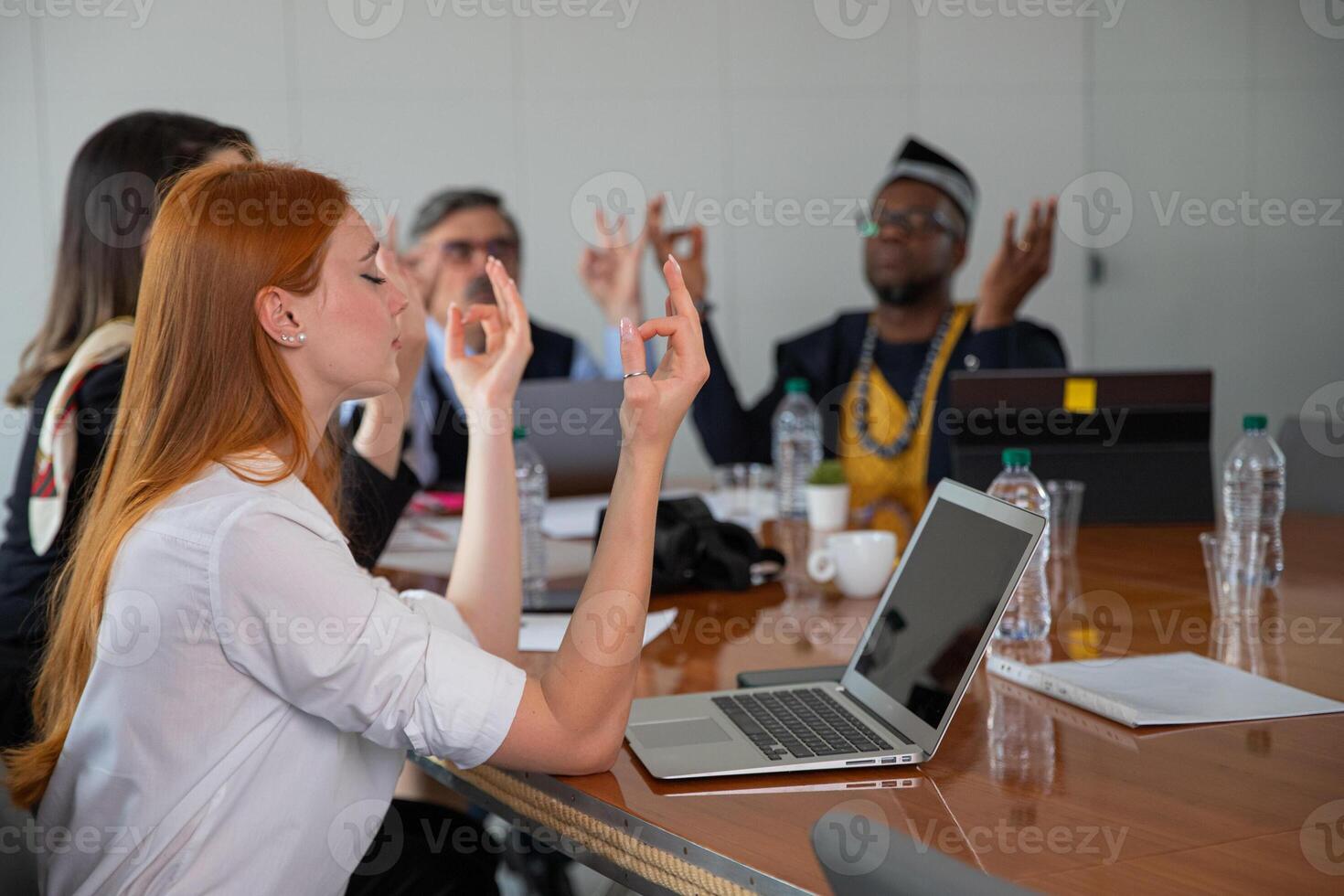 A multi ethnic group of business people do yoga exercises to relax in the office photo