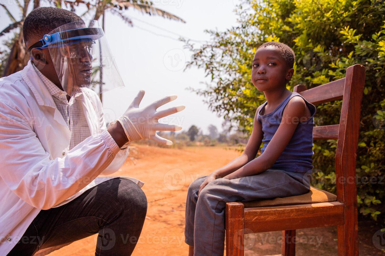 A pediatrician during a visit with a child sitting on a chair in Africa photo