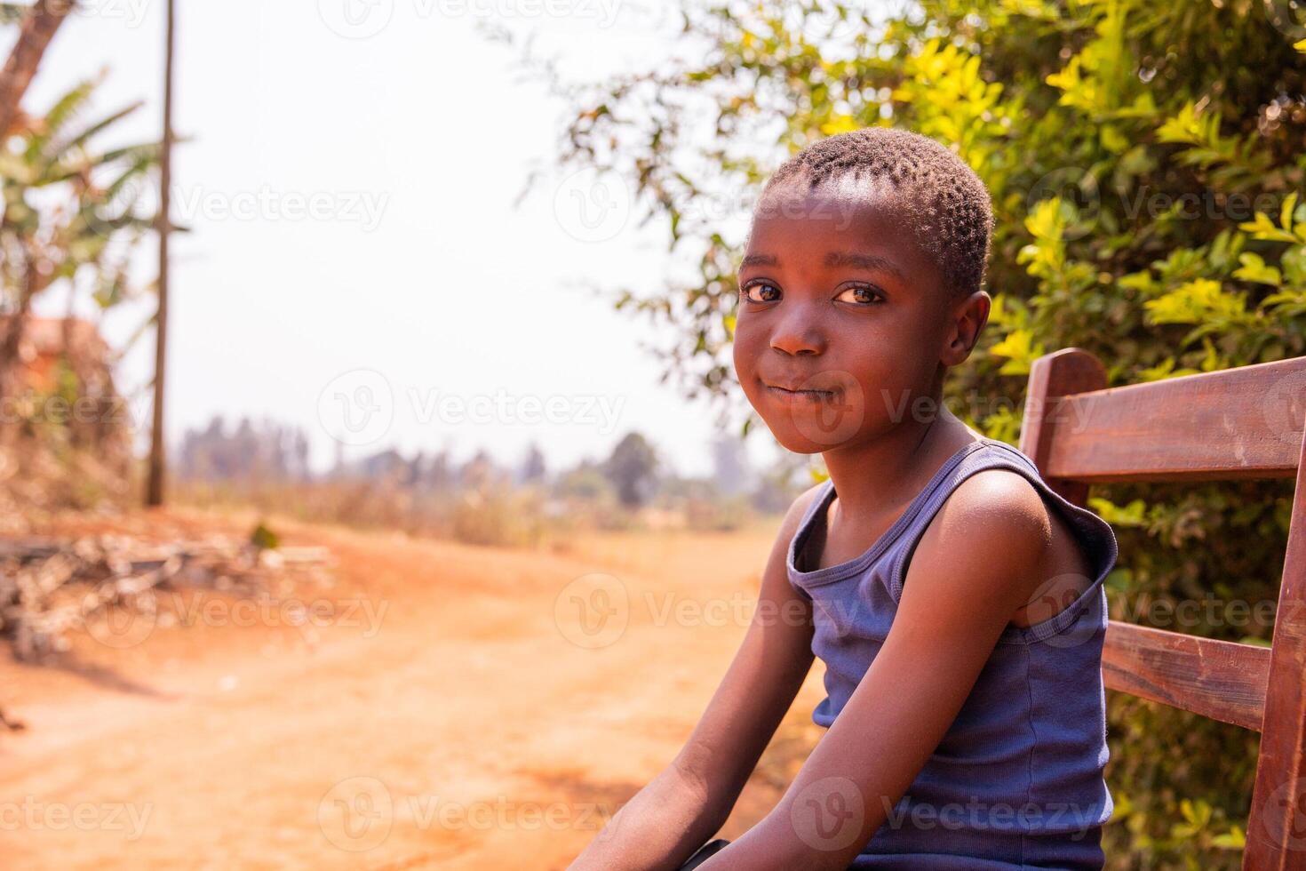 Portrait of a smiling African little boy sitting in a chair, innocent look, photo with copy space