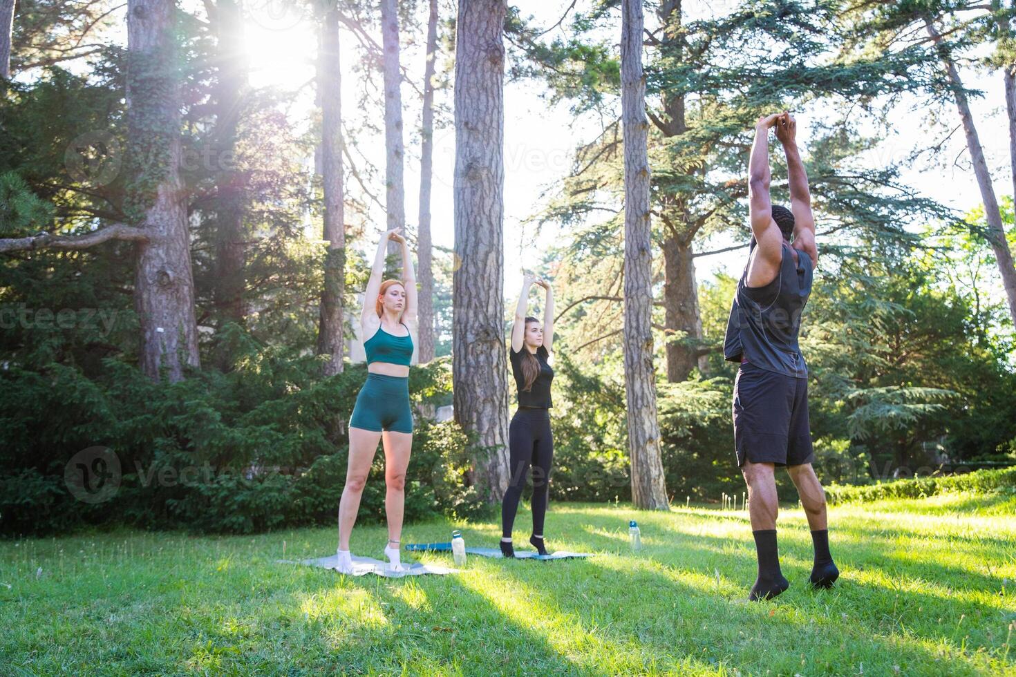 A fitness coach with his students during a class outdoors, healthy living concept photo