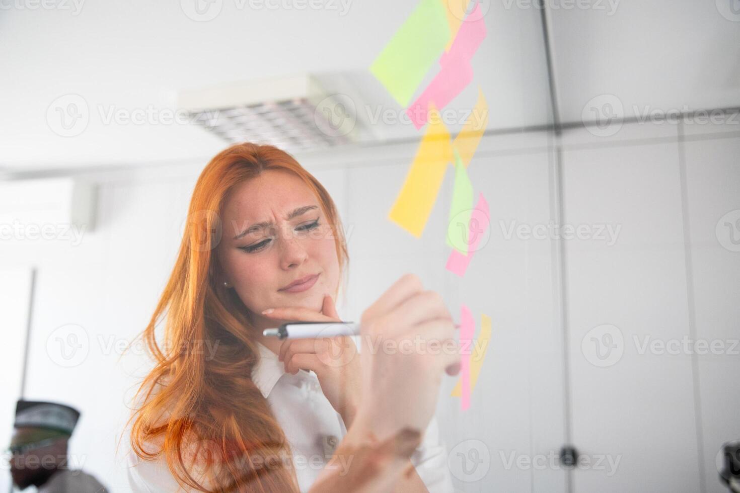 Pensive businesswoman writes on sticky notes, brainstorming in the office photo