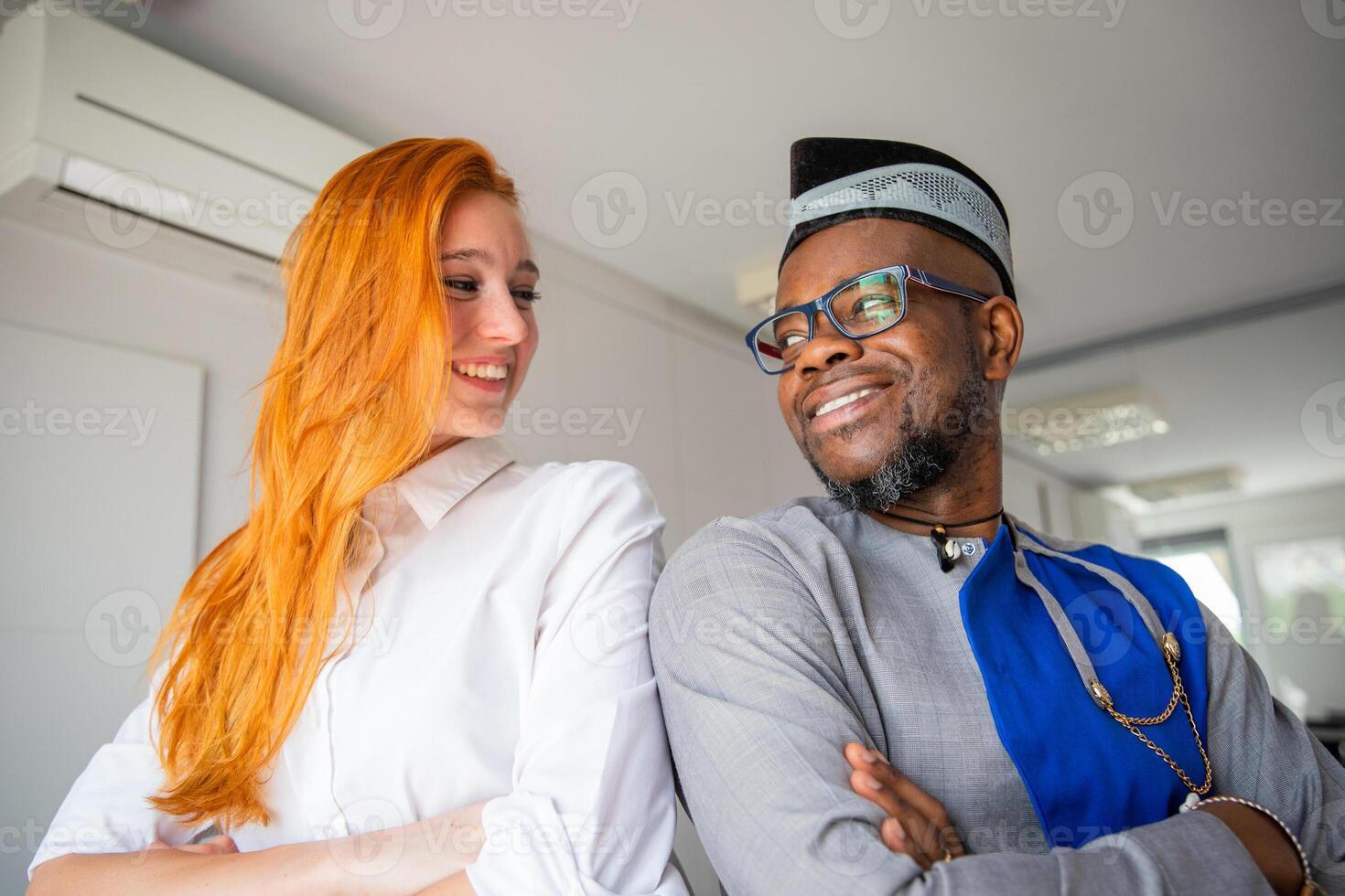 Two colleagues look at each other smiling in the office, happy business people of different cultures photo