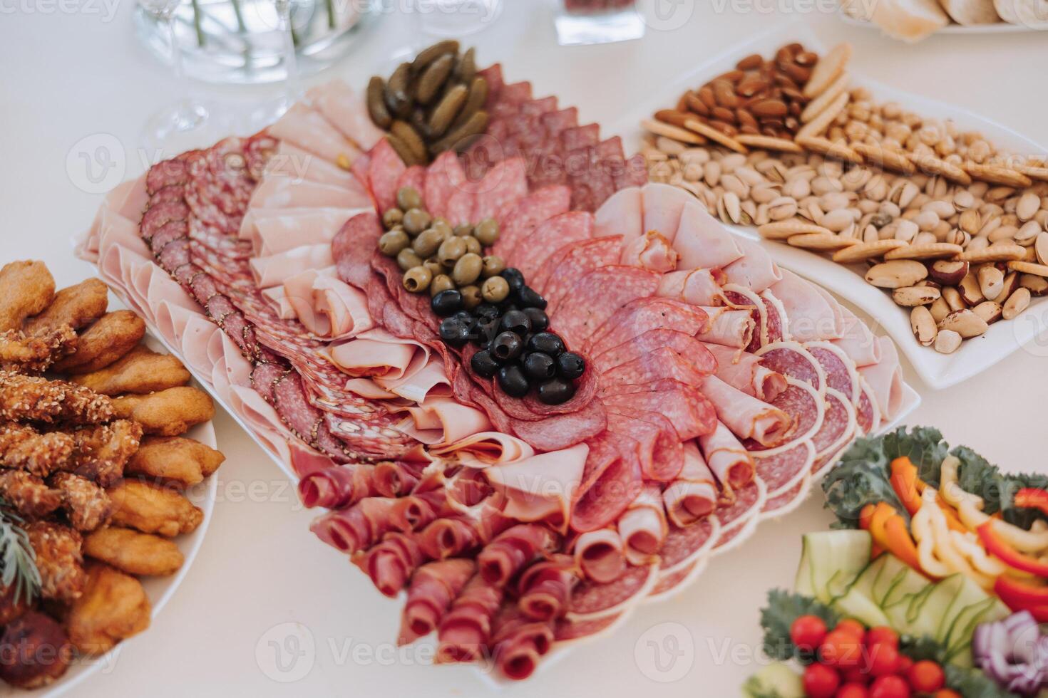 A table with a variety of food, including meats, vegetables, and crackers photo