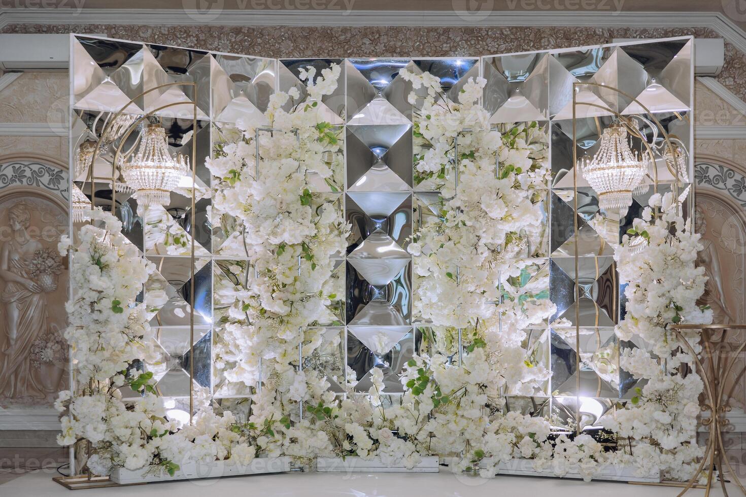 A large wall of white flowers with a gold frame photo