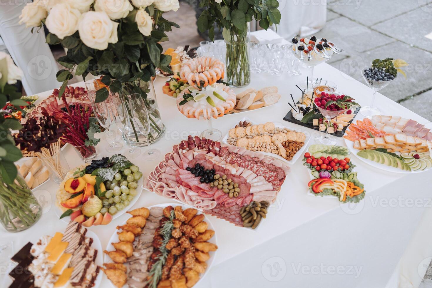 A table is covered with a variety of appetizers and desserts, including fruit photo