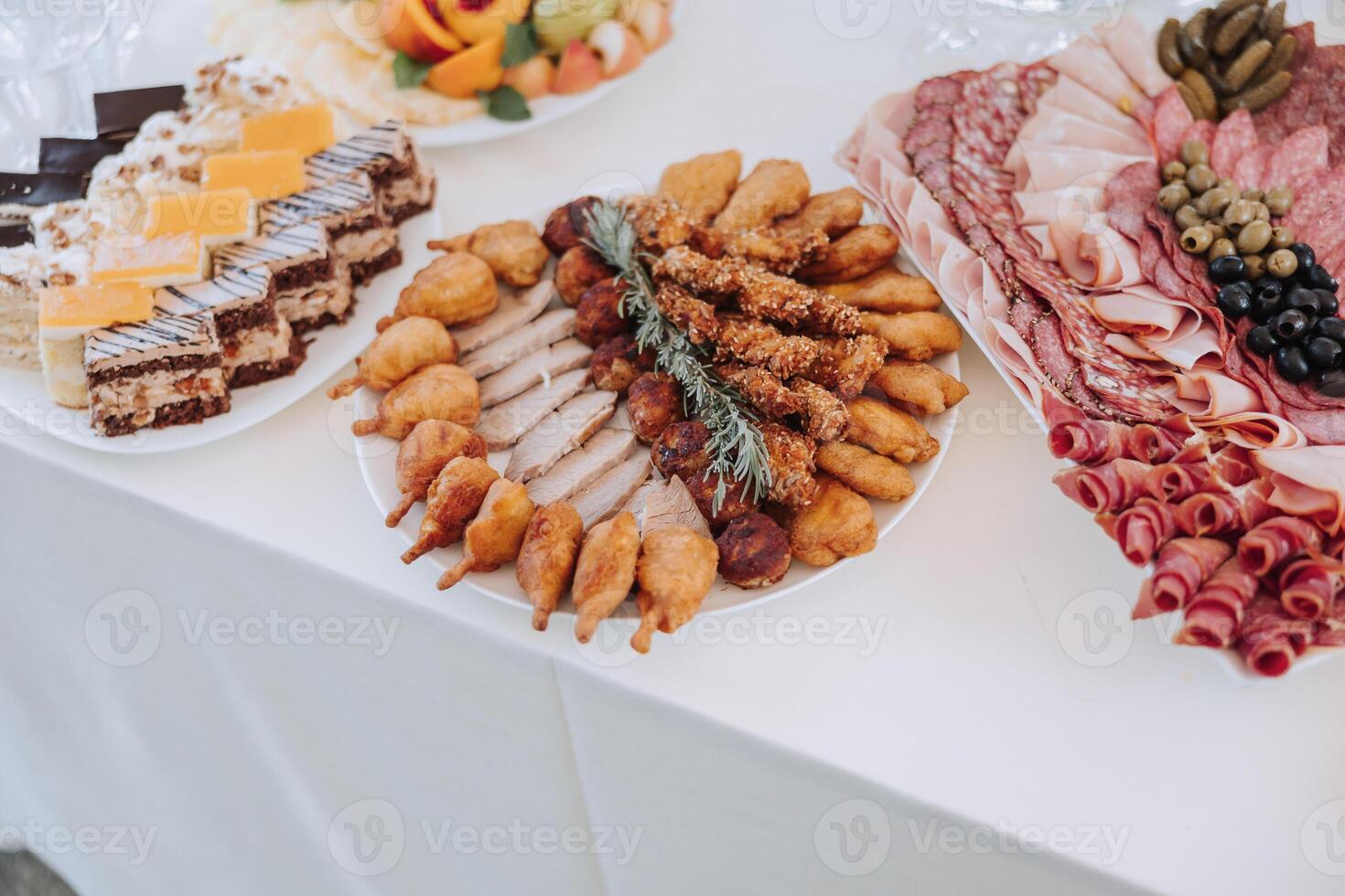 A table with a variety of food, including a plate of meat, a plate of vegetables photo