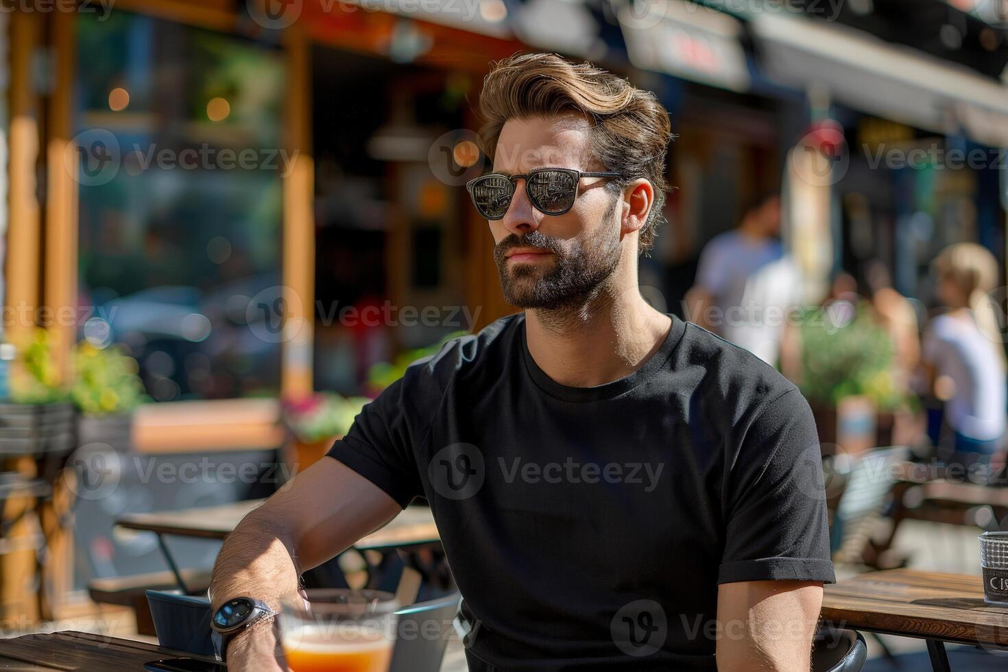 Man Wearing Black T-Shirt and Sunglasses Sits at Outdoor Cafe Table photo