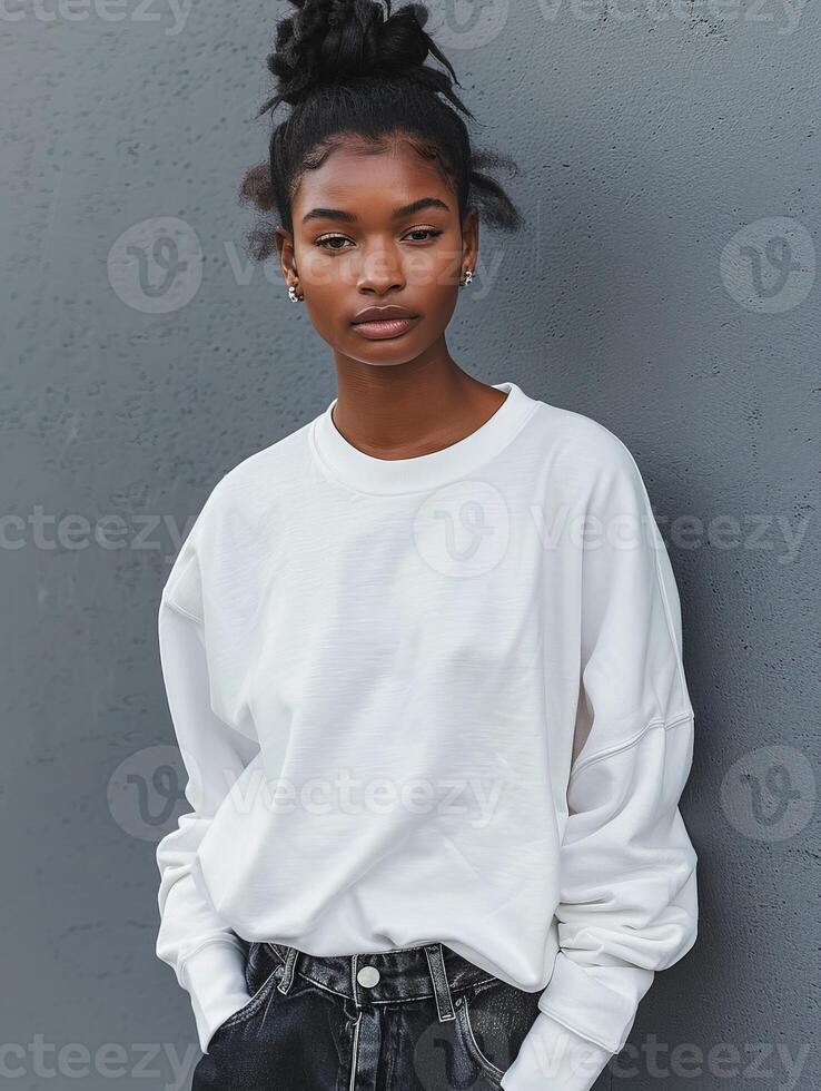 Stylish Black Woman Posing in White Sweatshirt Against Gray Wall photo