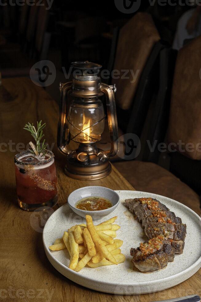 Plate of meat with fries, served with a berry drink on a table photo