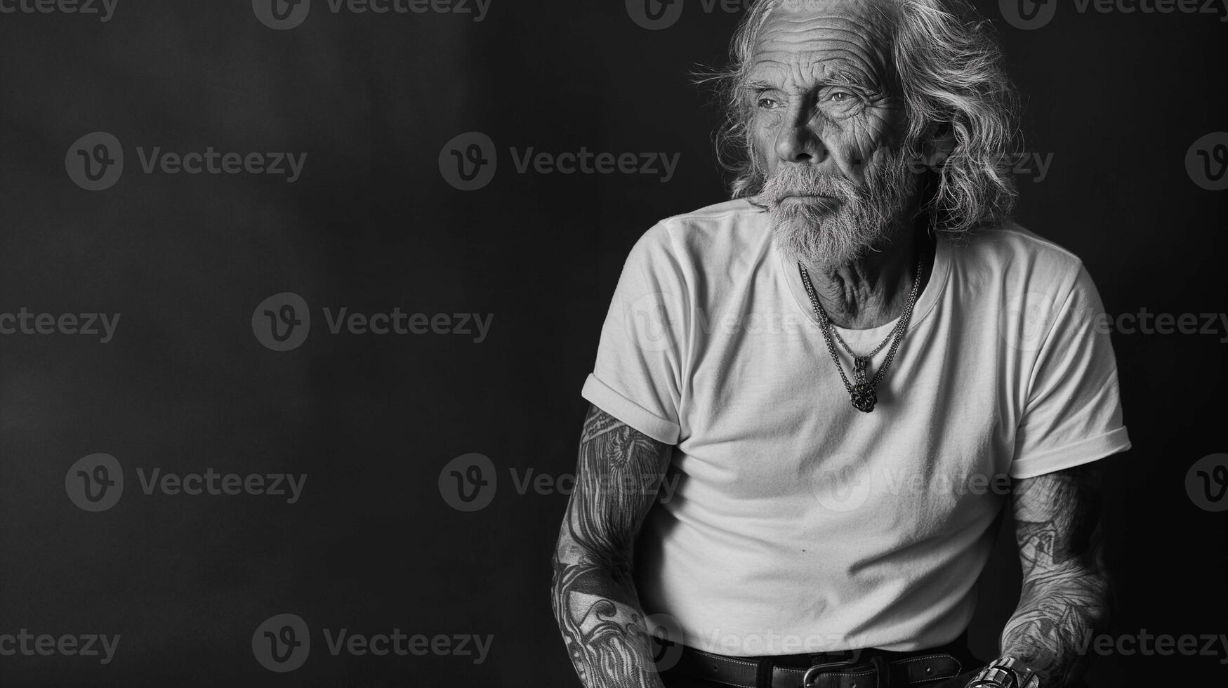Elderly tattooed man monochrome portrait image. Deep gaze black and white photography studio shot. Aged wisdom picture close-up. Life of experiences concept photo on dark background