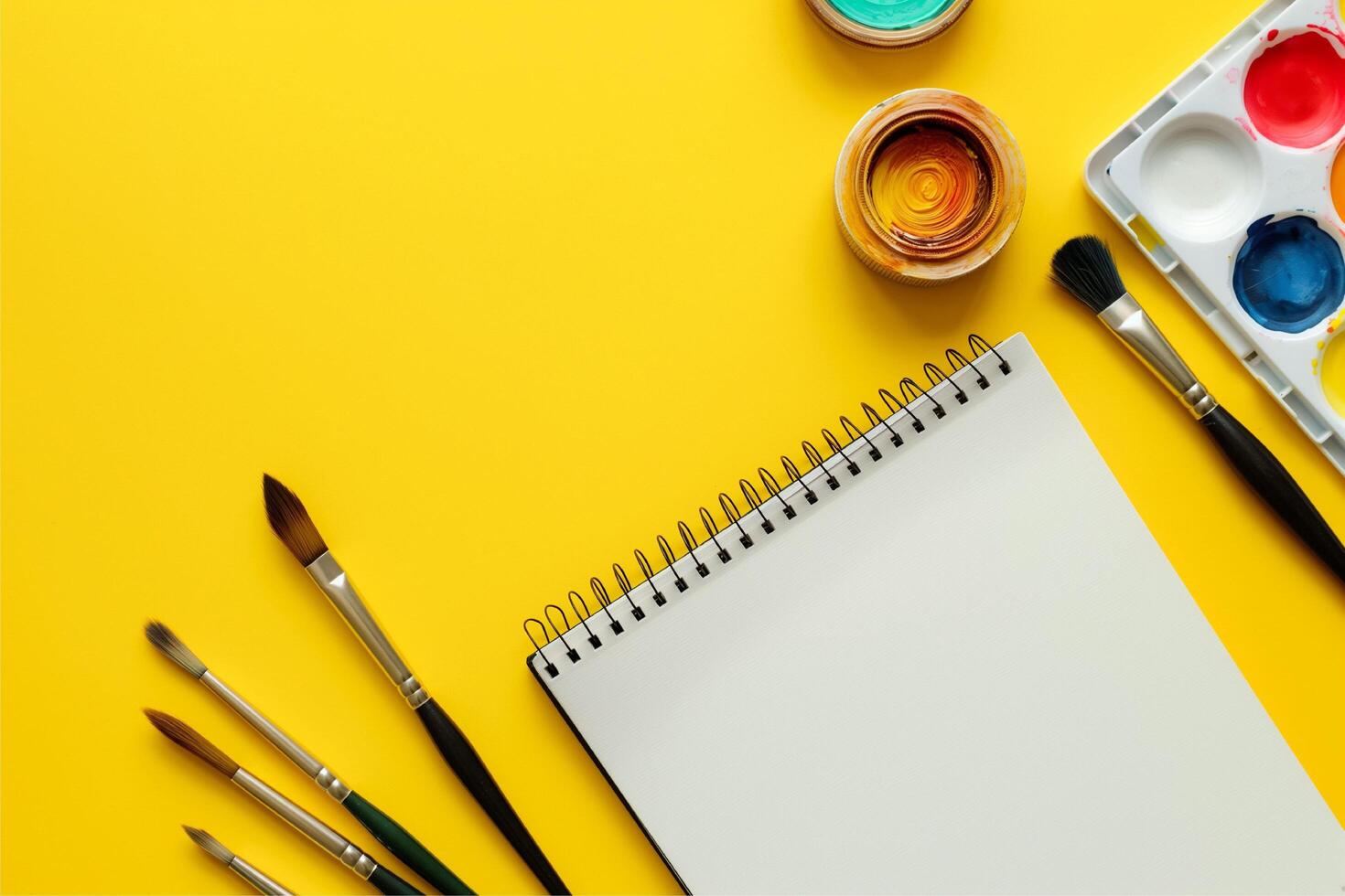 watercolor paints and brushes with notebook photo