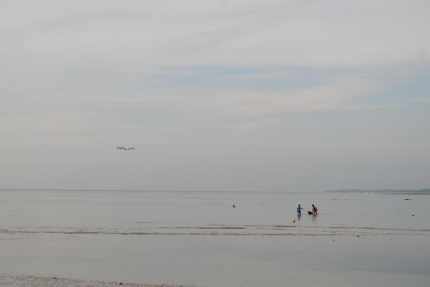 a person standing on a beach with a kite flying in the sky photo