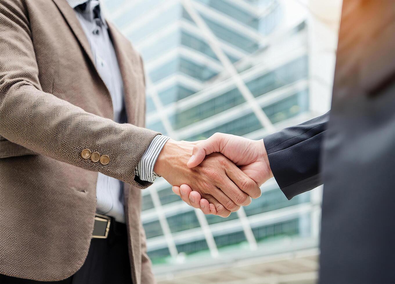 Close up of hand of Two business people shaking hands,blurred building background photo