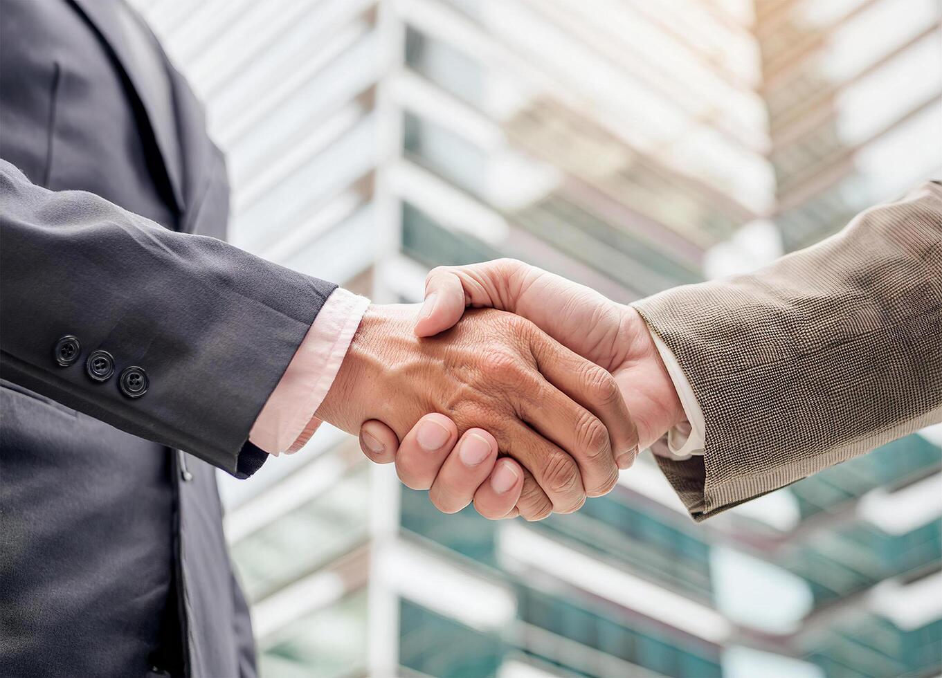 Close up of hand of Two business people shaking hands,blurred building background photo