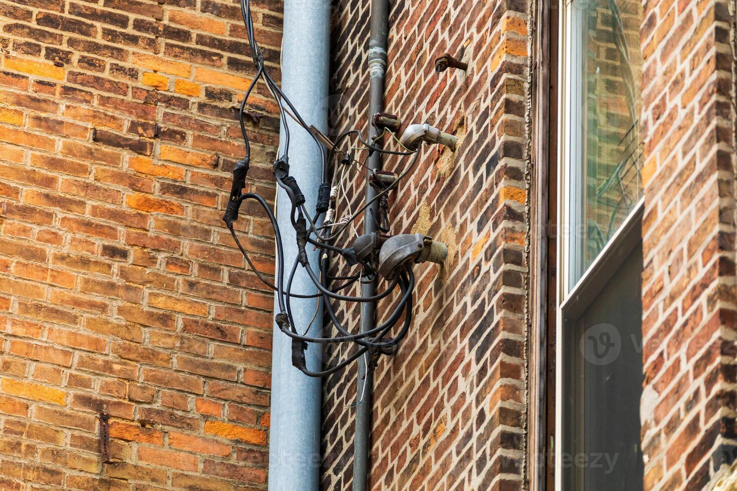 metal pole on the side of a building sprouting a number of electrical connections photo