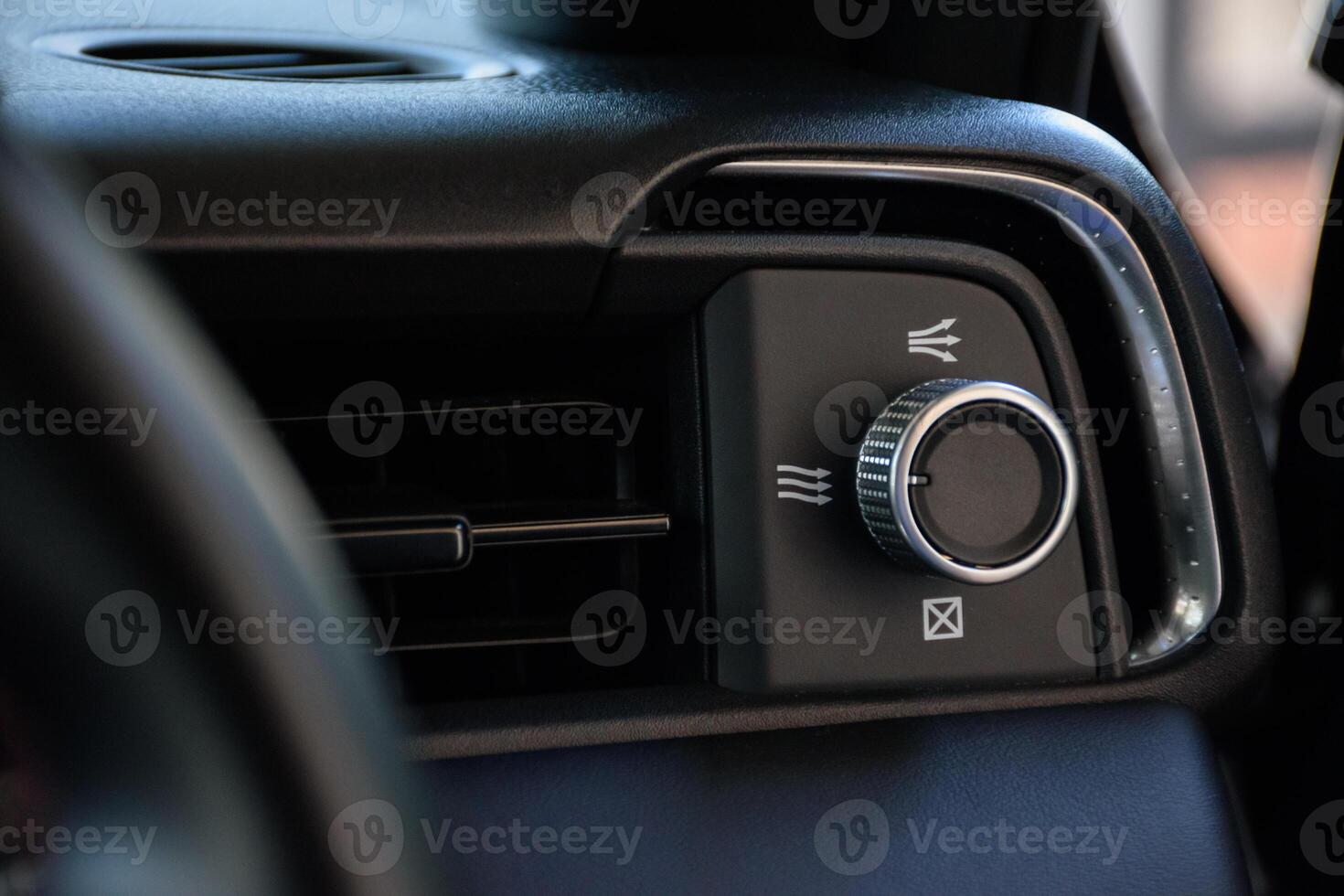 Close up of a modern car air conditioning mode button used to adjust the level of air inside the car or change the mode of the air conditioner in a modern dark black tone. photo