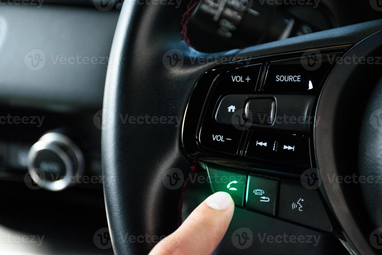 Fingers pressing the answer call button on the car steering wheel with green light of a modern car luxury in 2024. photo