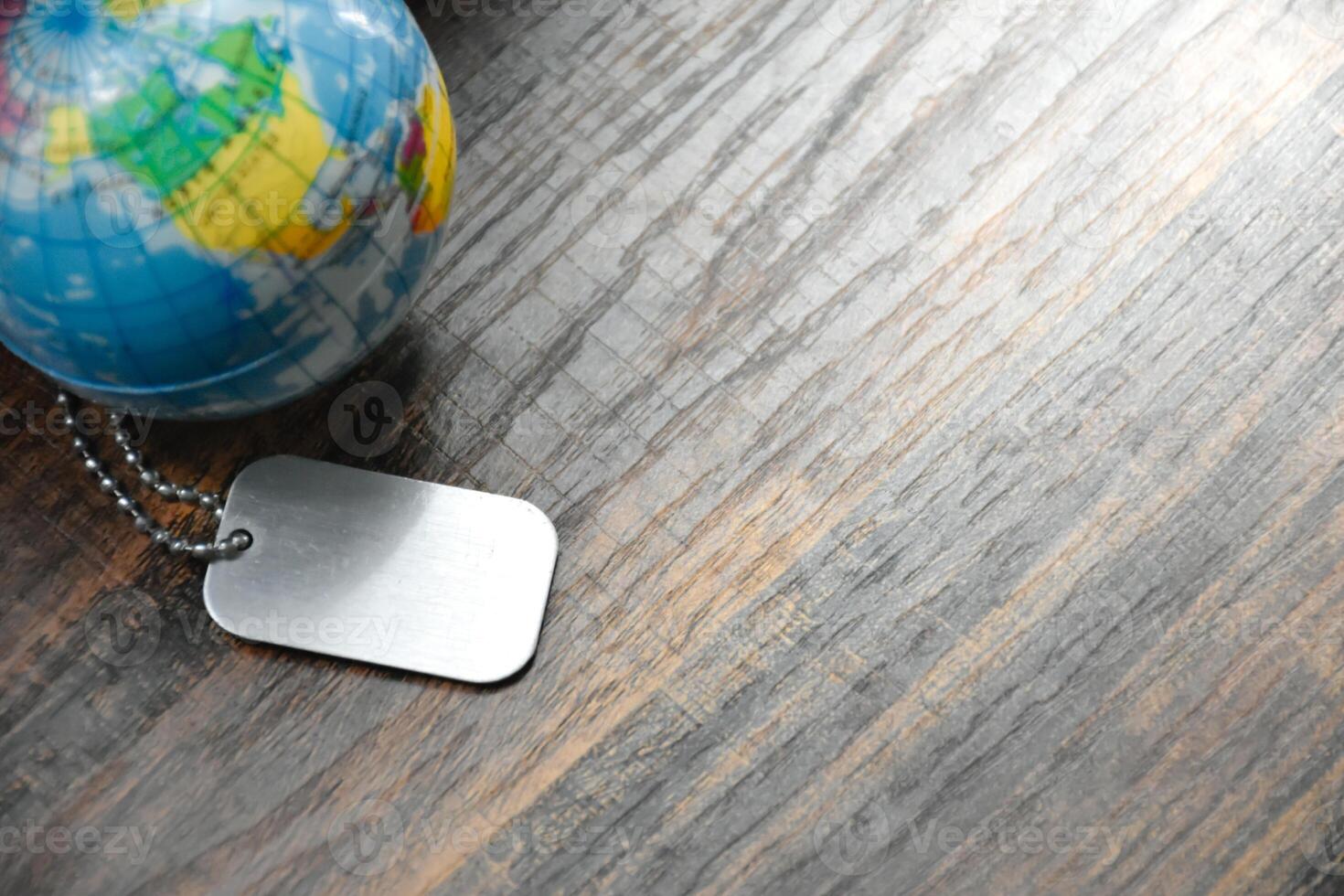 Dog Tag and Earth Globe on wood pattern work desk and soft sunlight background,Desktopequipment,Dog Tag empty,World and map of Americas,Top view with copy space,Concept of Travel and Work,Earth map photo