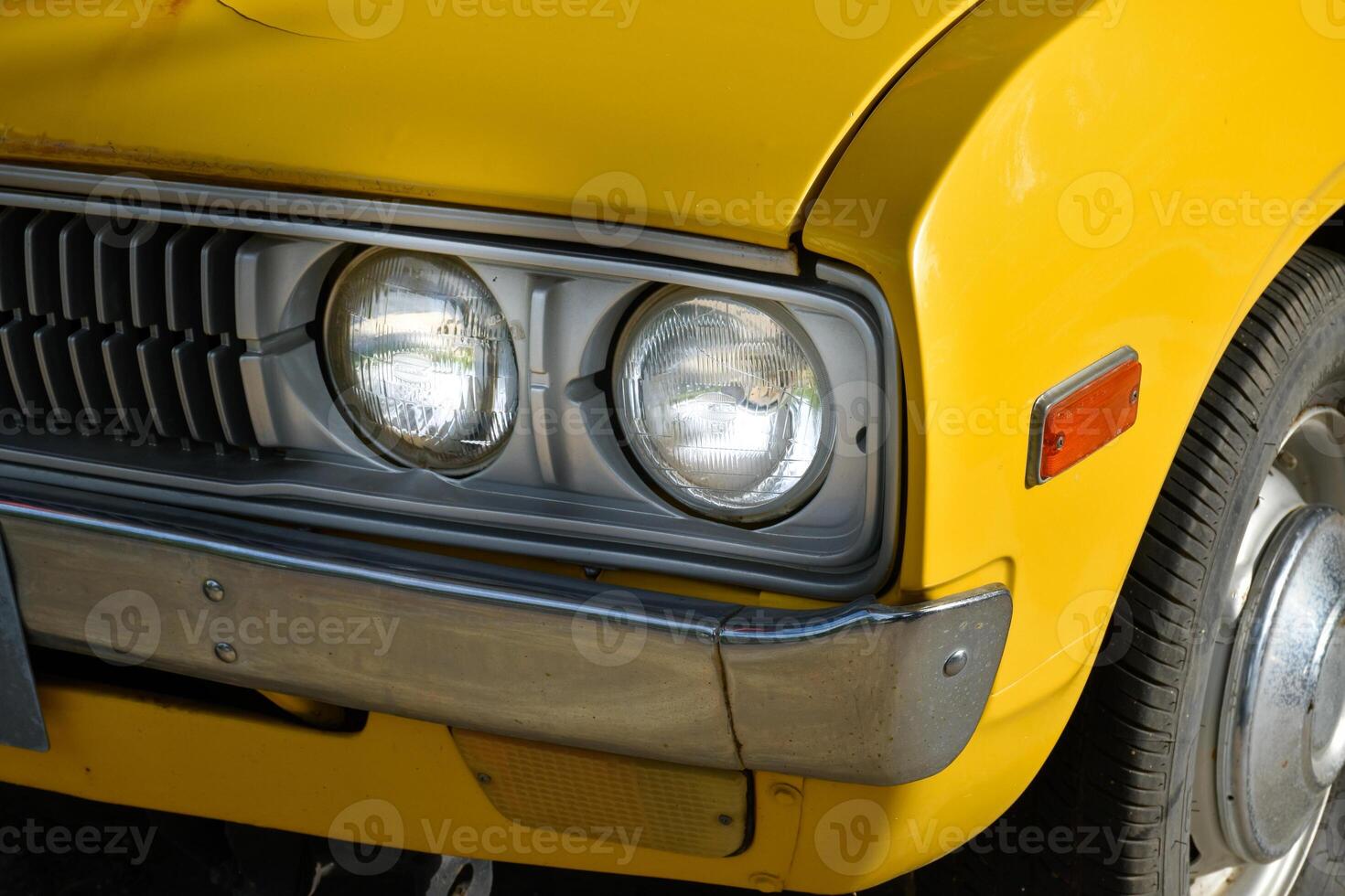 Front of classic retro car yellow,car tires and circle headlight car, headlight of a car,front light details yellow car,charm of classic retro cars. photo