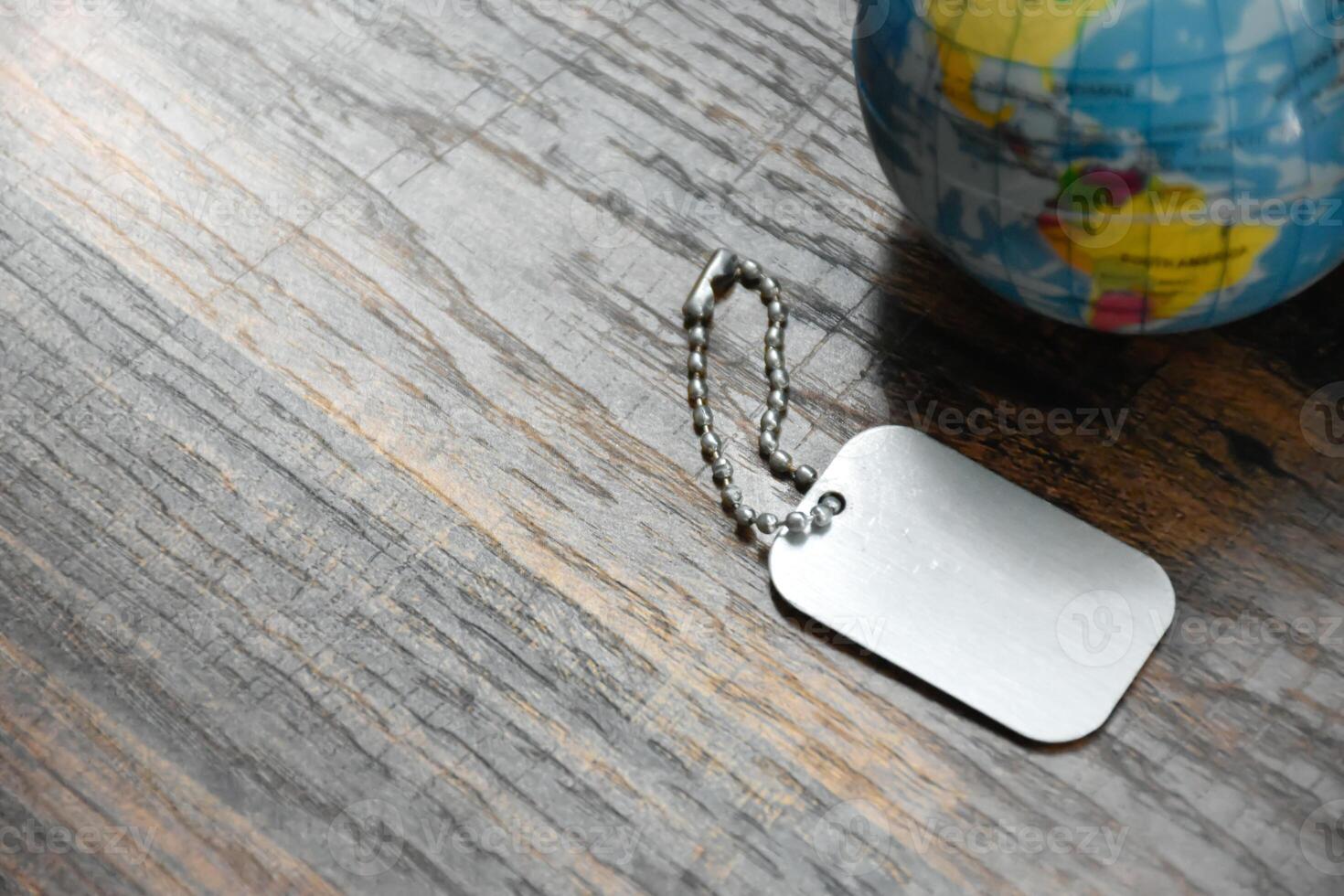 Earth Globe and Dog Tag on wood pattern work desk and soft sunlight background,World and map of Americas,Dog Tag empty,Desktop equipment,Concept of Travel and Work,Top view with copy space,Earth map. photo
