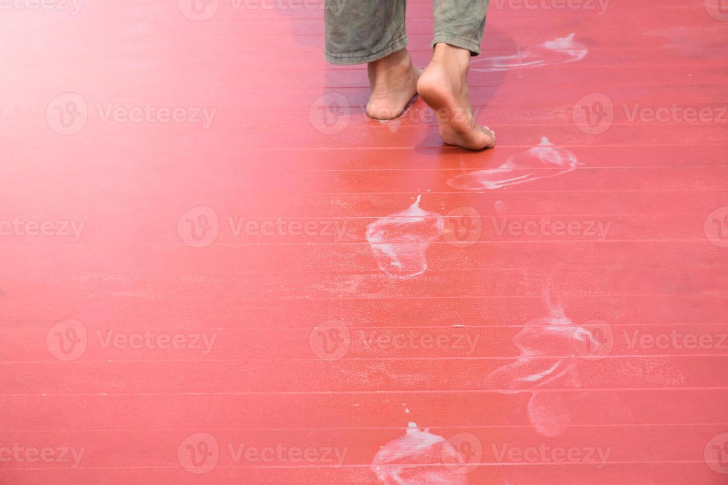 Man feet walking and white footprints on red wood floor in soft sunlight blurred background for concept of dirty marks and theft. photo