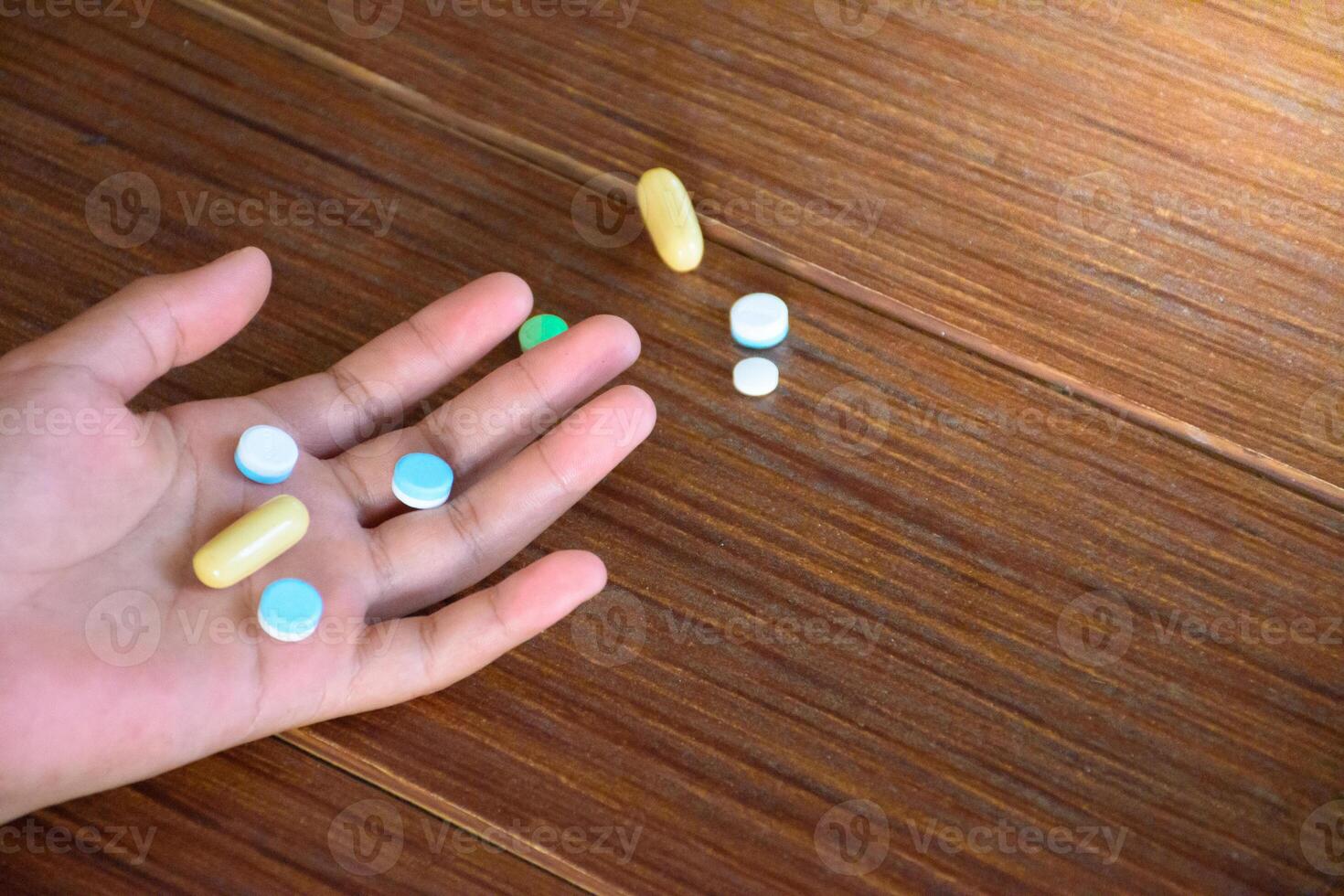 Hand and many colorful pills on wood pattern floor top-view for concept of overdose and medicine. photo