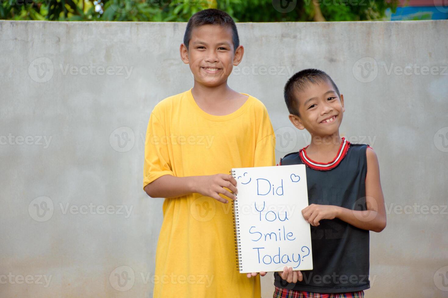 Two asian young boys holding a sign or piece of paper with the word did you smile today for concept of encouragement and living happily. photo